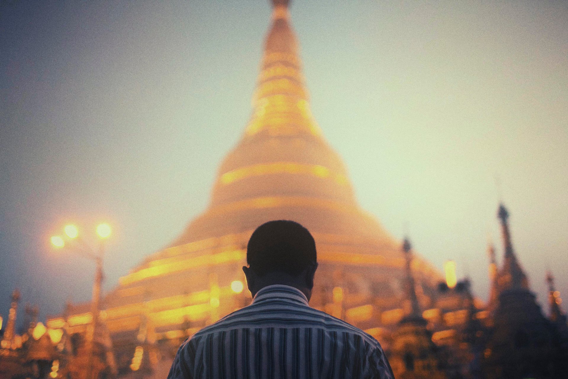 Homme devant la pagode dorée Shwedagon, Myanmar, crépuscule